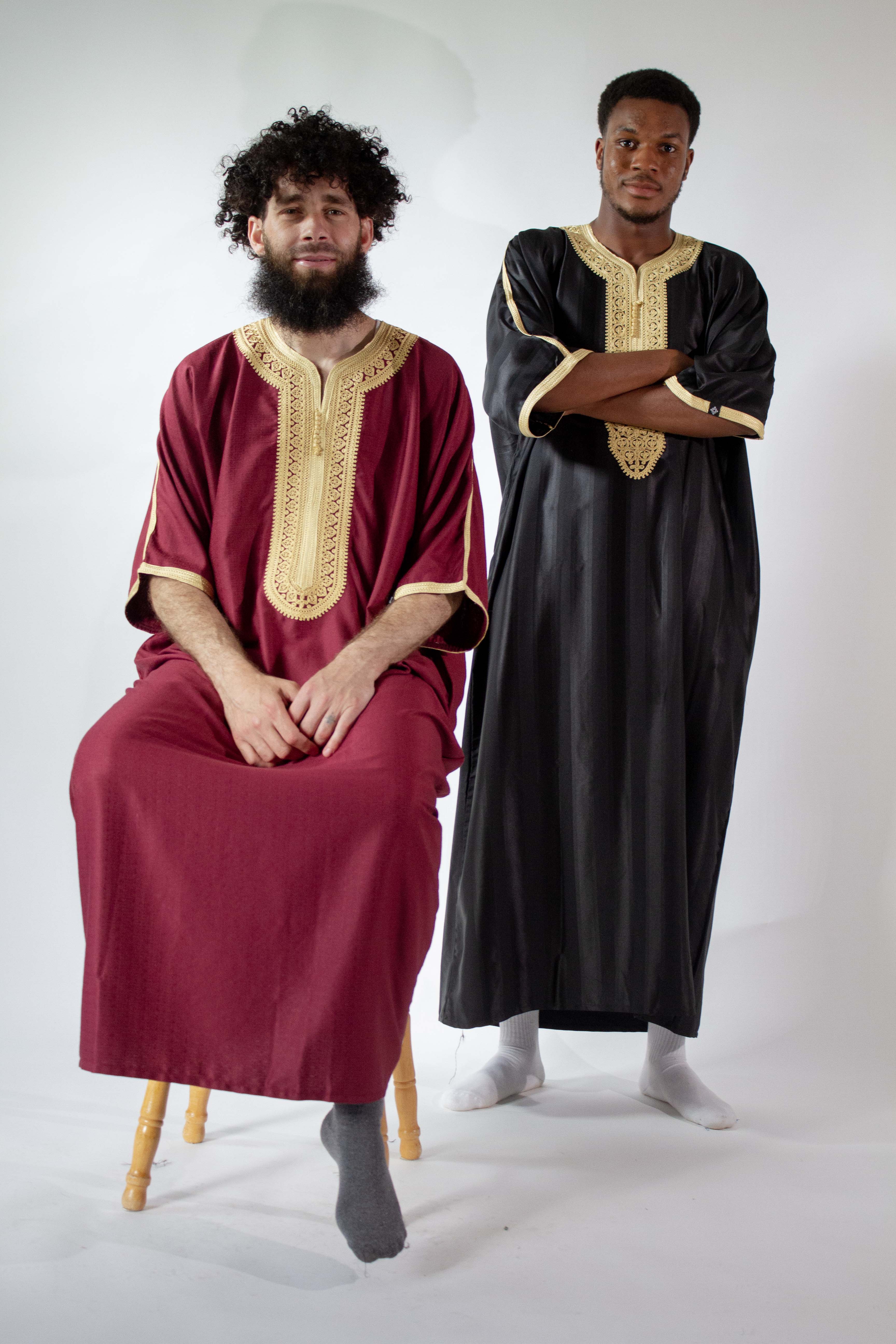 two men wearing moroccan thobes. black and gold jawhara. maroon and gold in linen